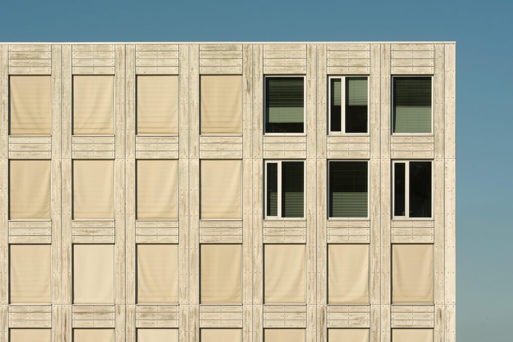Contemporary wooden building facade with repetitive window pattern under clear sky.