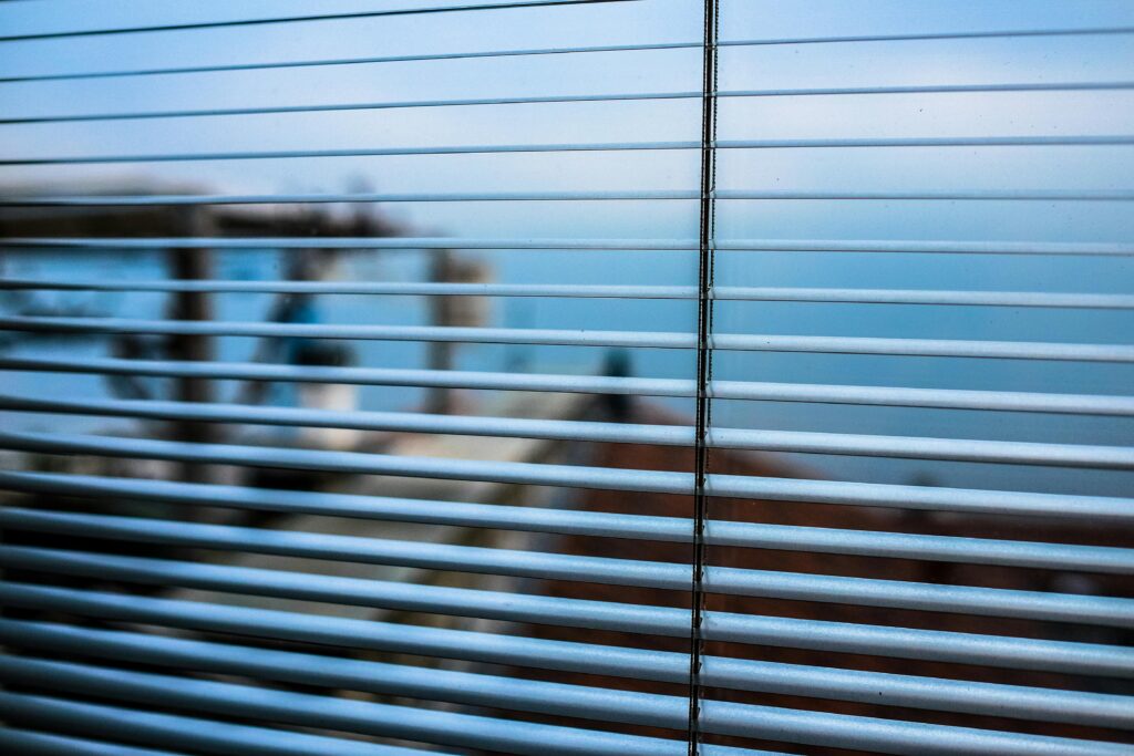 Blurred outdoor scene visible through modern window blinds, creating a tranquil ambiance.