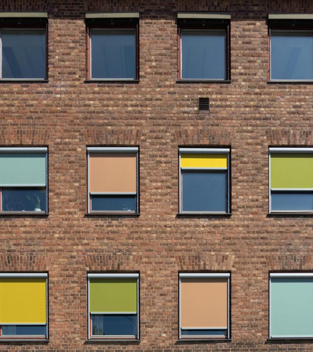 A brick building facade with colorful blinds in Fredrikstad, Norway, creating a lively pattern.